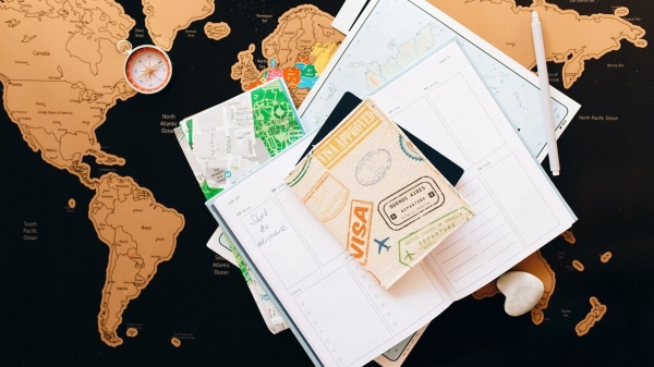 A pile of travel-related documents stacked on a map of the world
